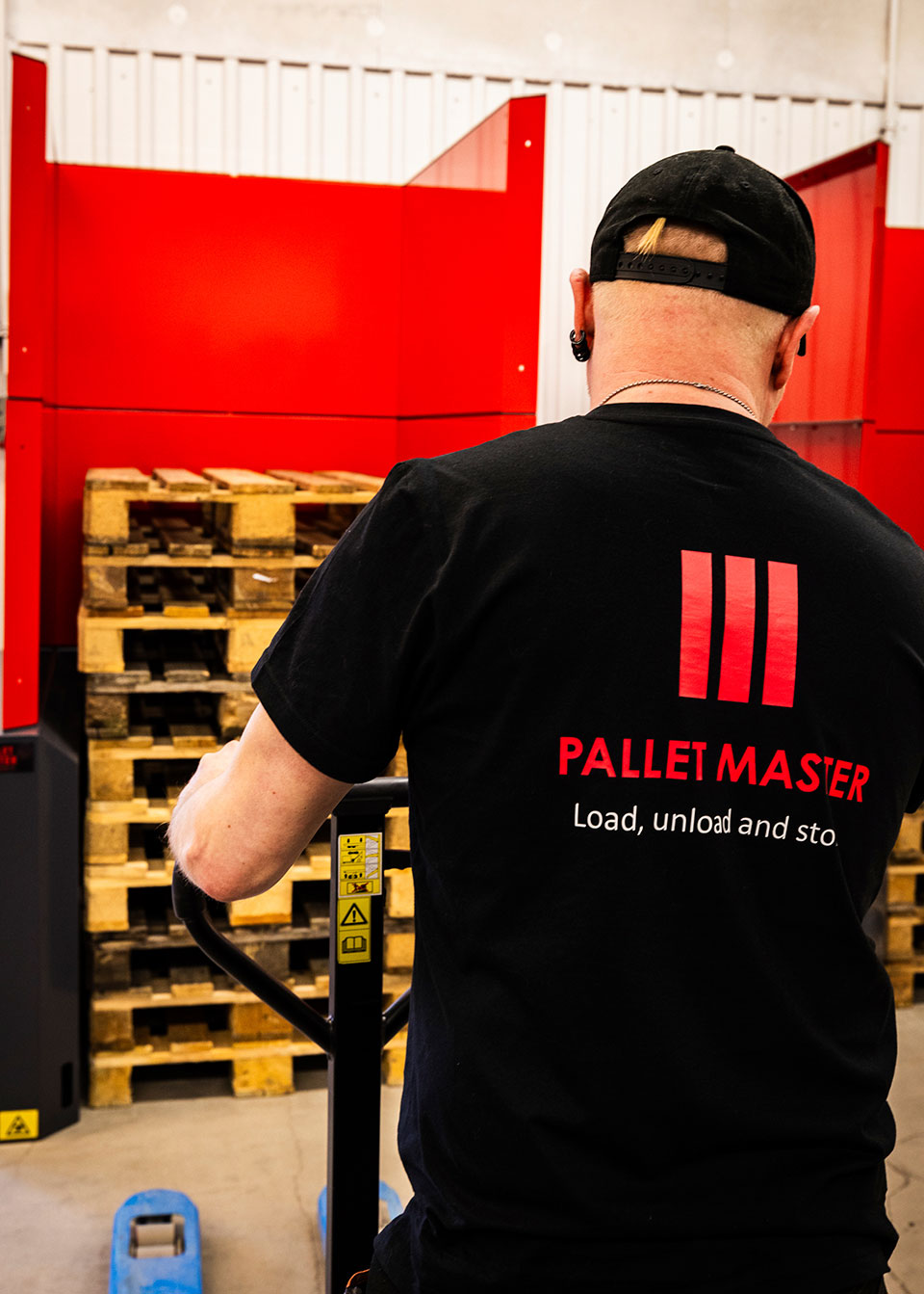 Man approaching a PalletMaster® dispenser with an empty pallet jack