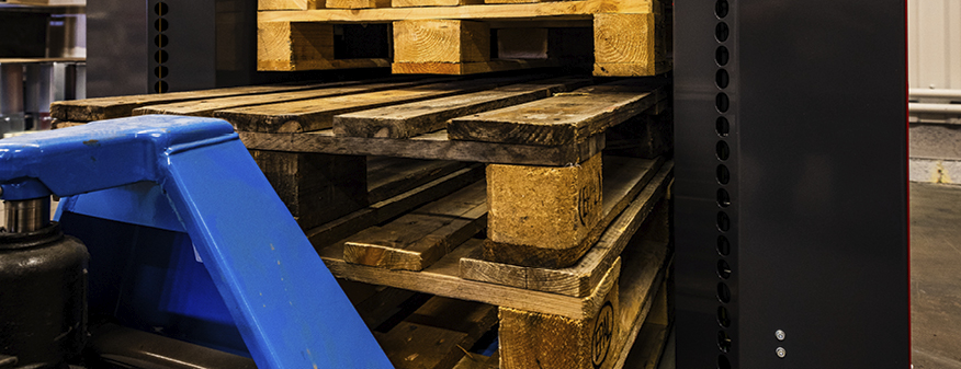 Empty wooden pallets being unloaded from an automatic pallet dispenser