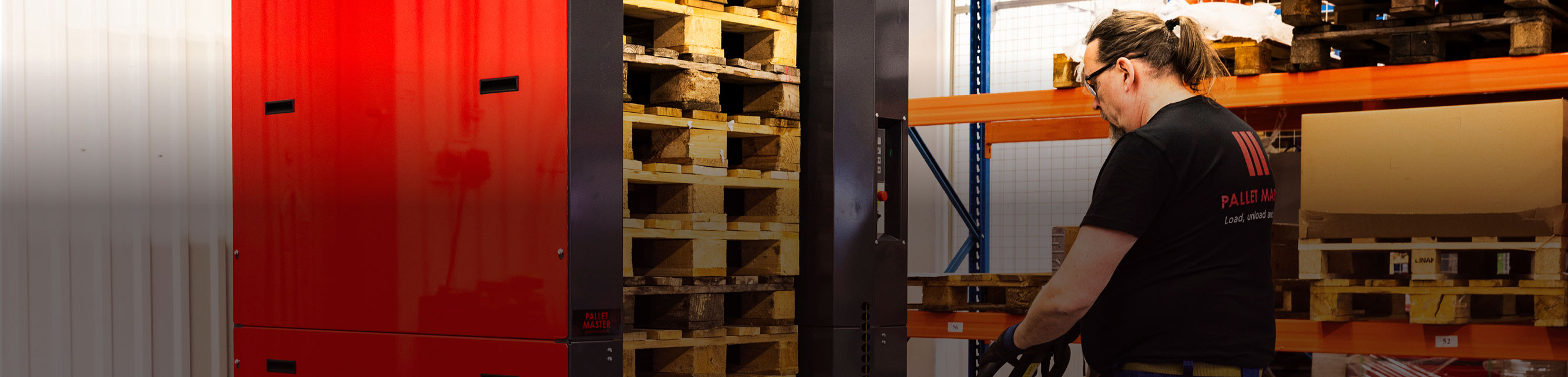 Man with a PalletMaster® dispenser and wooden pallets stacked inside the dispenser