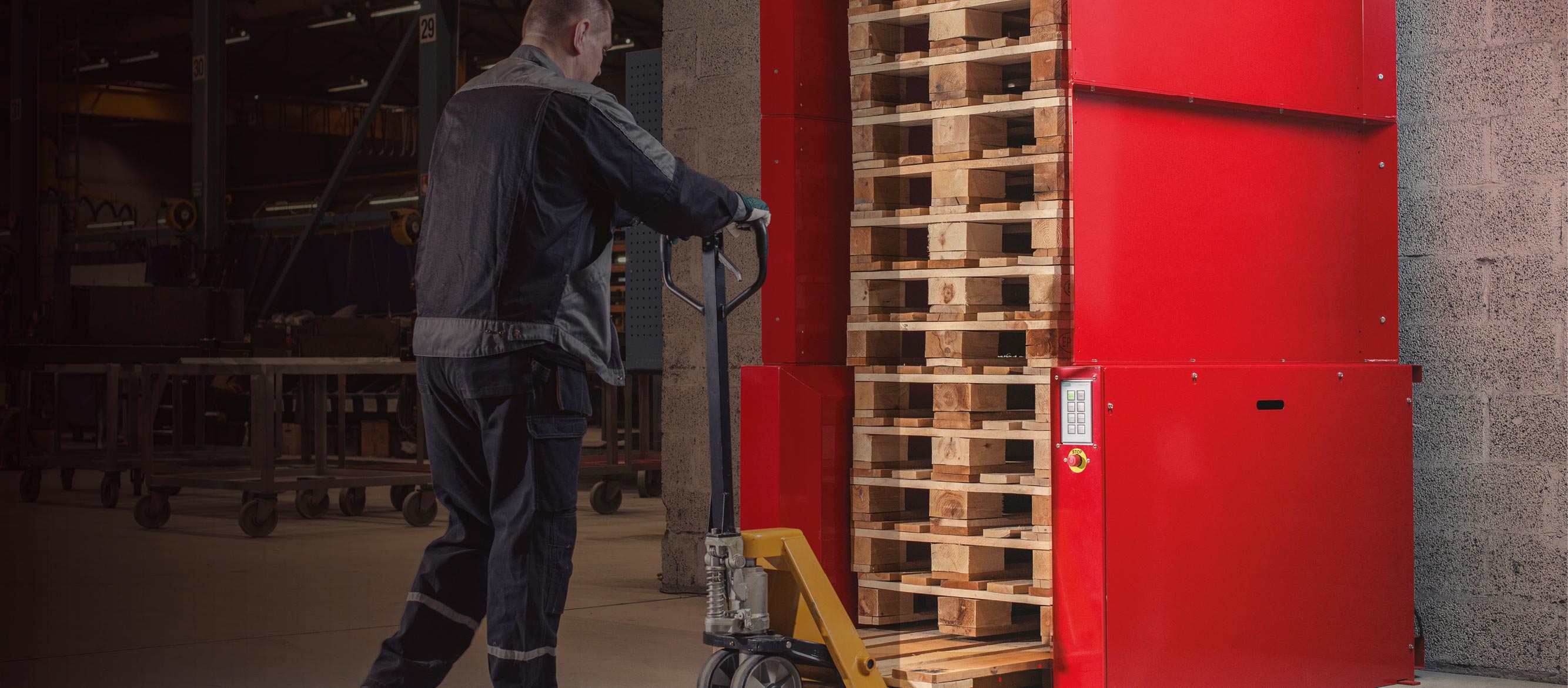 Man with a pallet jack loading one new empty pallet underneath a stack of pallets in a PalletMaster® dispenser