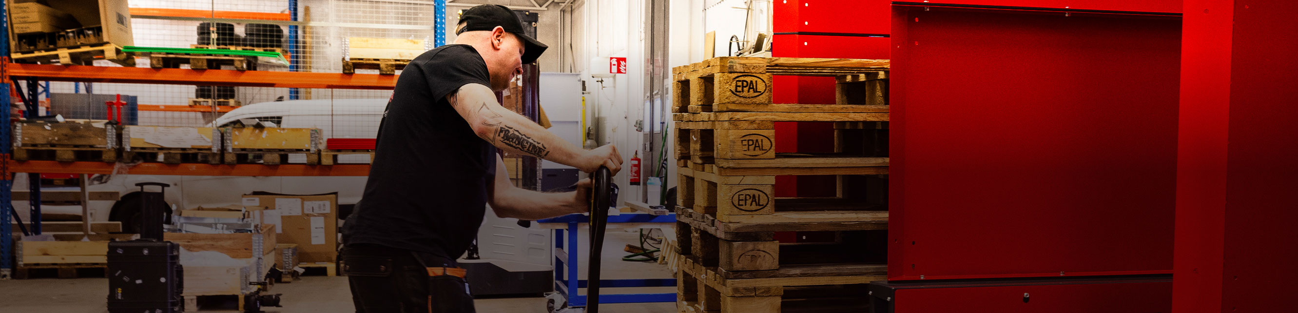 Man with a pallet jack unloading a stack of wooden pallets from a PalletMaster® dispenser